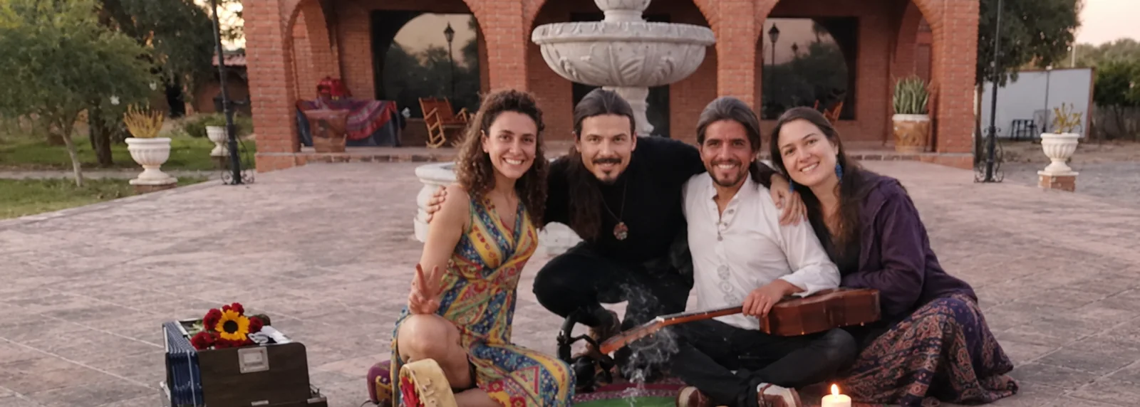 El equipo de Ayahuasca México sentado junto a un altar de flores en el patio, al atardecer