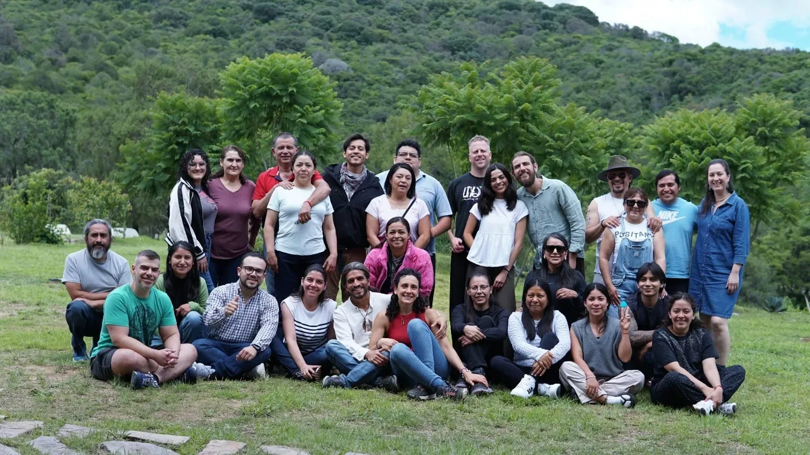 Grupo de participantes reunido en el jardín, con el cerro al fondo